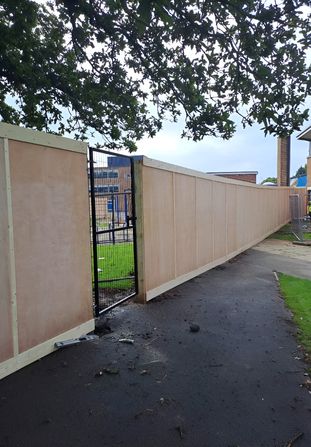 dug-in timber hoarding with pedestrian gate