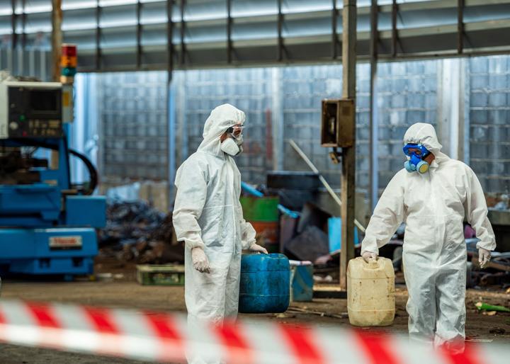hazardous waste site clearance with two people fully in PPE cleaning and removing waste