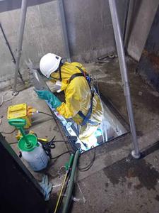 person in PPE climbing down ladder to investigate sewage issue