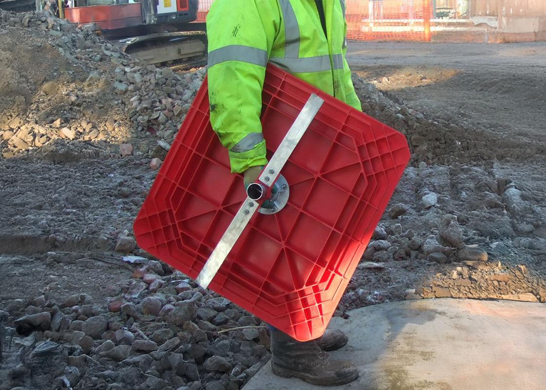 View of the underside of Temporary Manhole Cover while being carried by a man